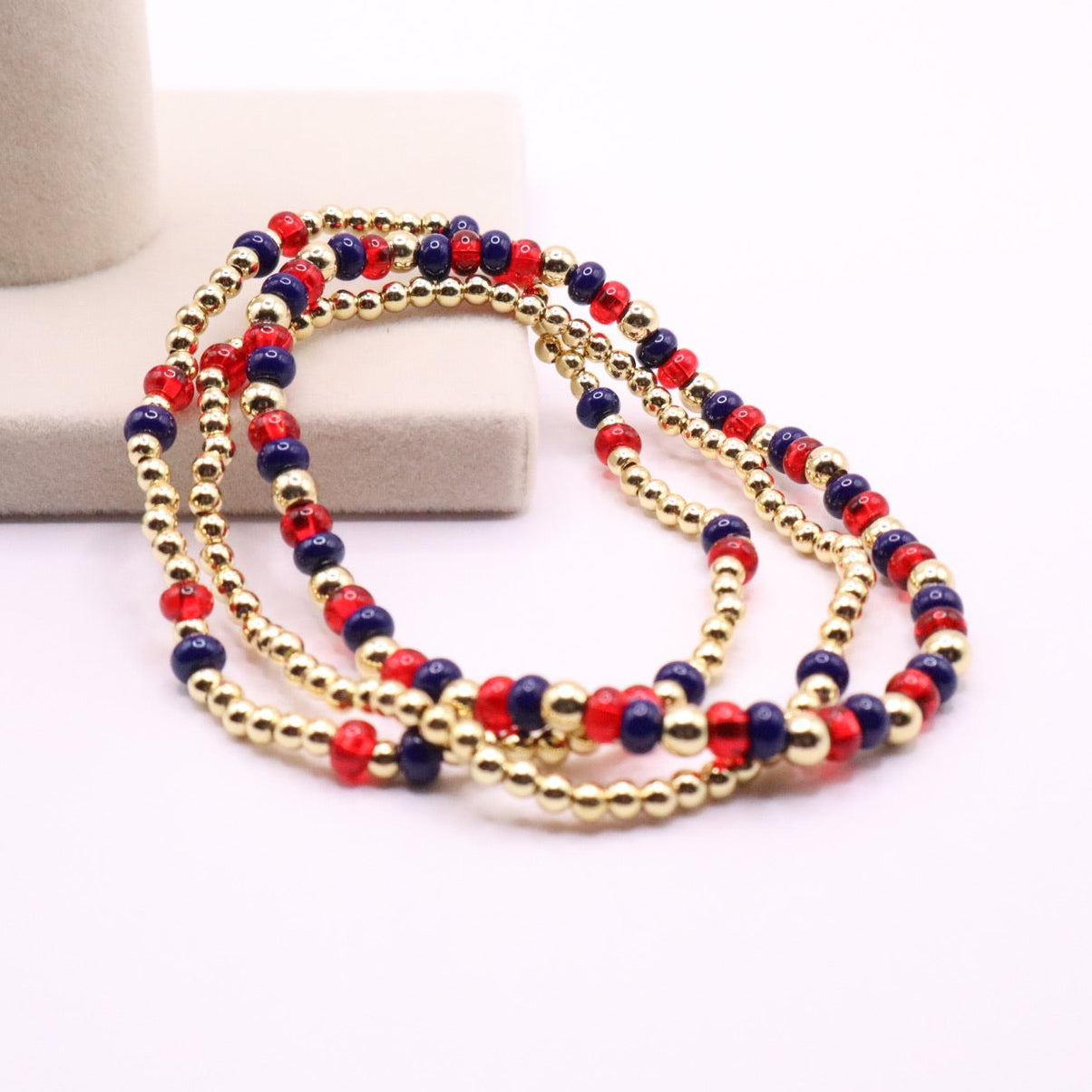 Multistrand beaded bracelet with red, blue, and gold beads on a white surface.