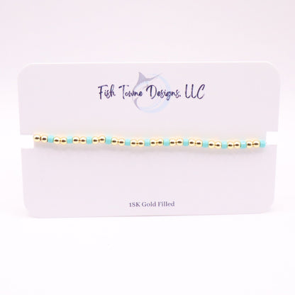 Gold and turquoise beaded bracelet on a Fish Towne Designs, LLC branded card.