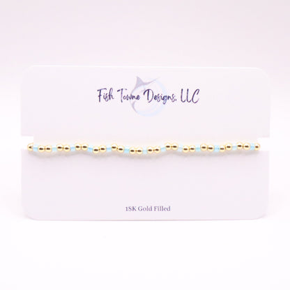 Gold and pale blue beaded bracelet on a white card with 'Fish Towne Designs, LLC' branding.