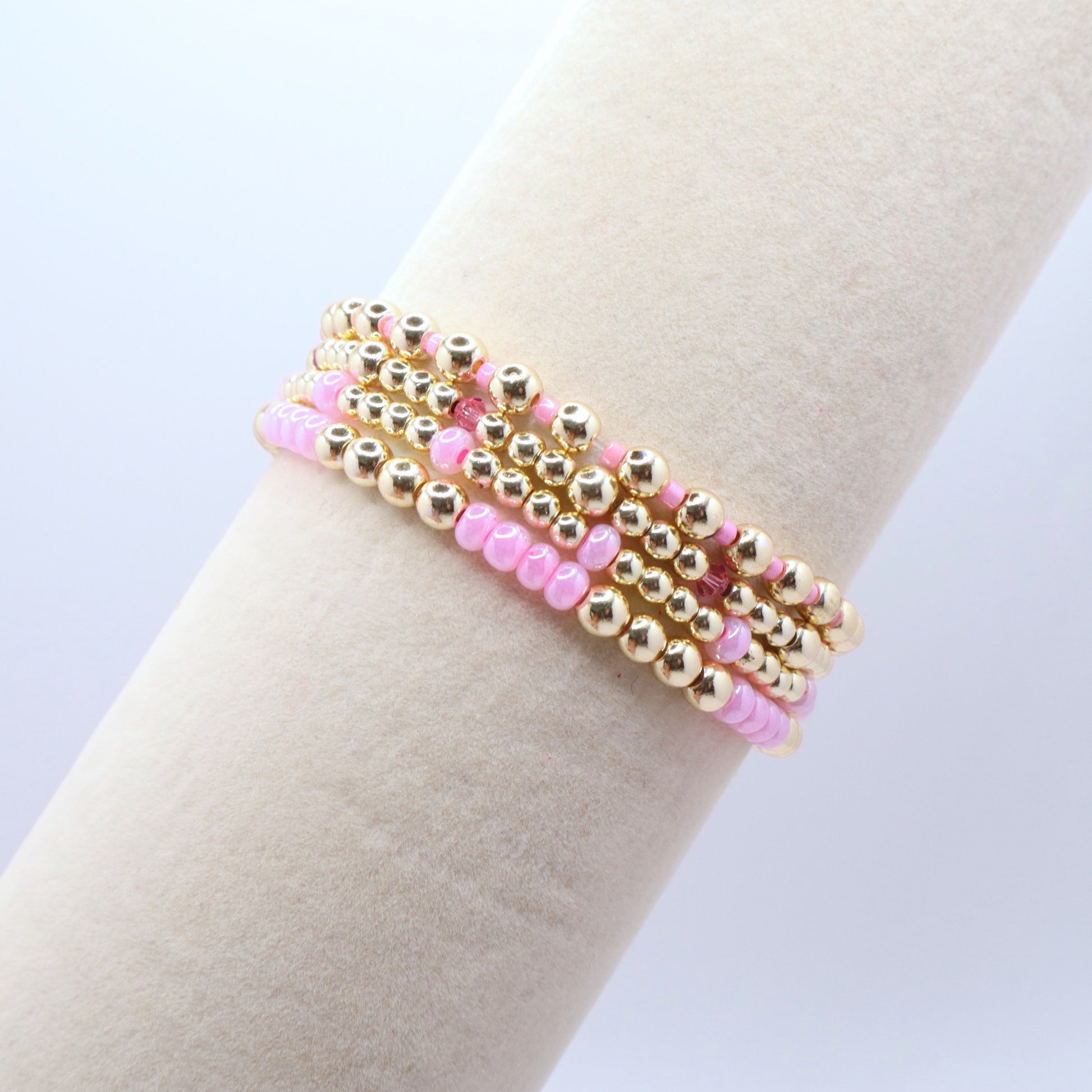 Handmade stretch bracelet set with polished gold hematite beads and pink crystal details.