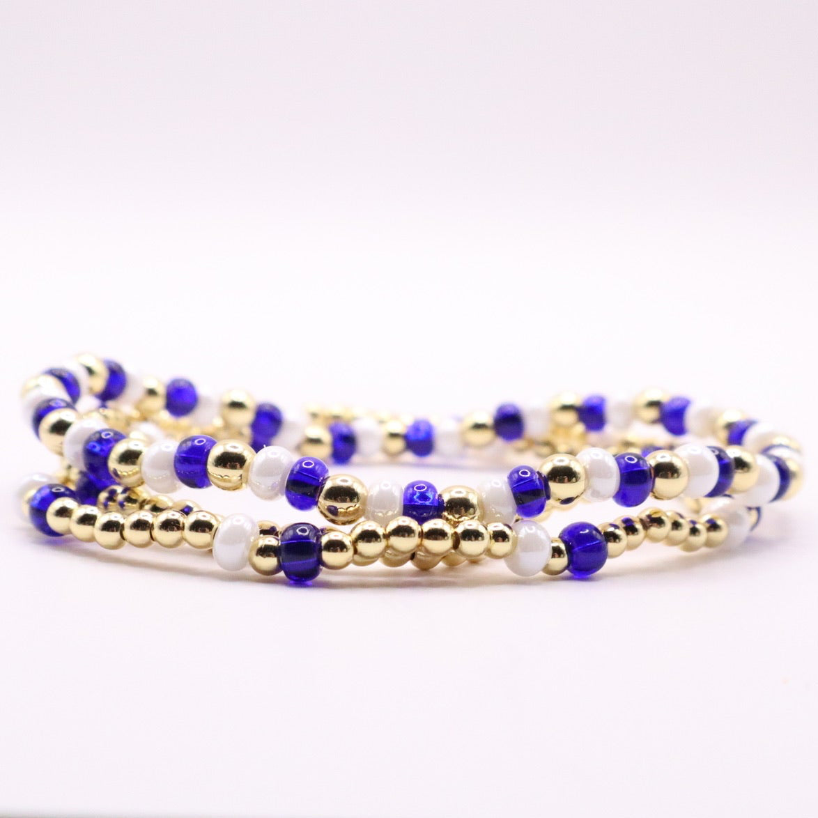 Three blue, white and gold bracelets on a white background