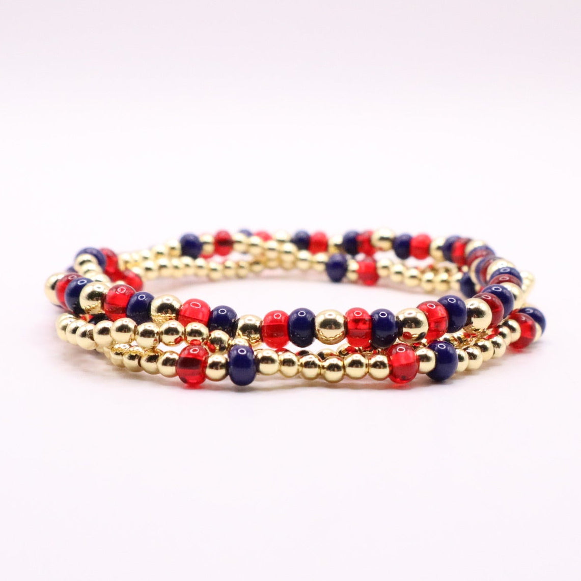 Set of beaded bracelets with gold, red, and blue beads on a white background