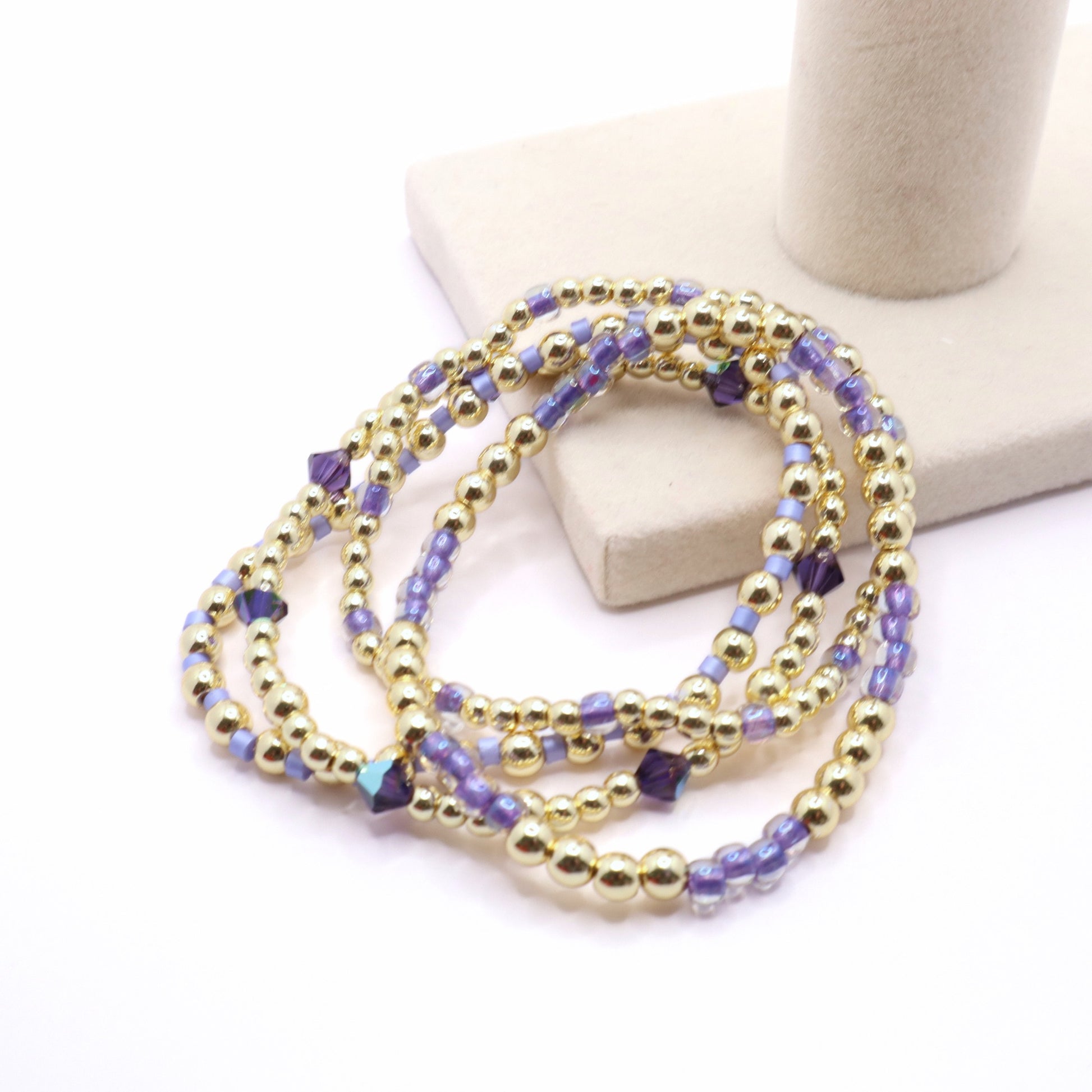 Coastal-inspired beaded bracelet stack in soft lavender, purple, and gold tones.