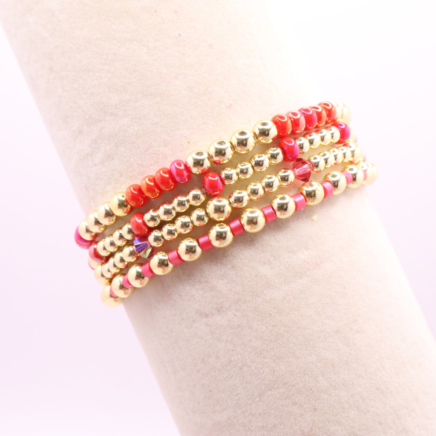 Colorful pink bracelet stack displayed on a jewelry card with gold-tone beads.