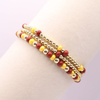 Three burgundy and gold bracelets on a display