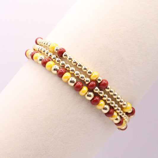 Three burgundy and gold bracelets on a display