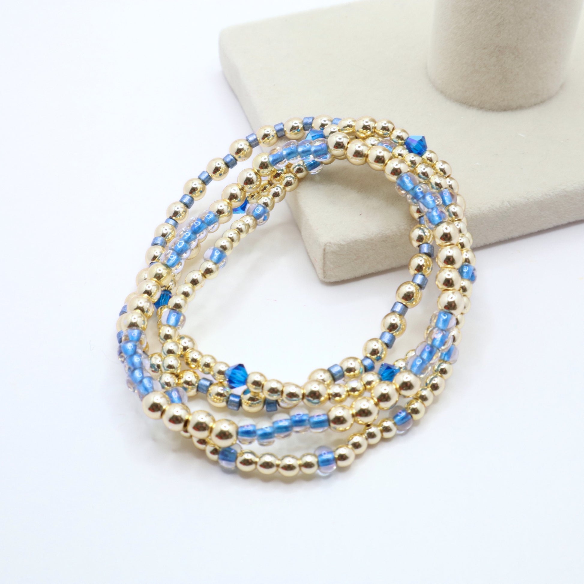 Coordinating four-piece bracelet set with gold beads and sparkling blue crystals.