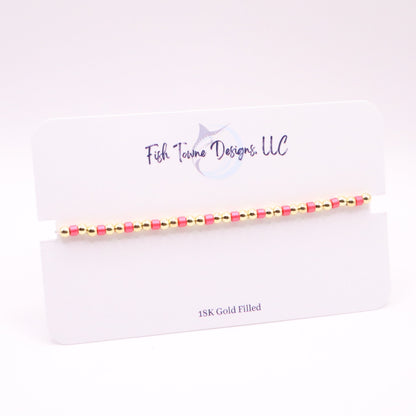 Gold and pink beaded bracelet on a white card with 'Fish Towne Designs, LLC' branding.