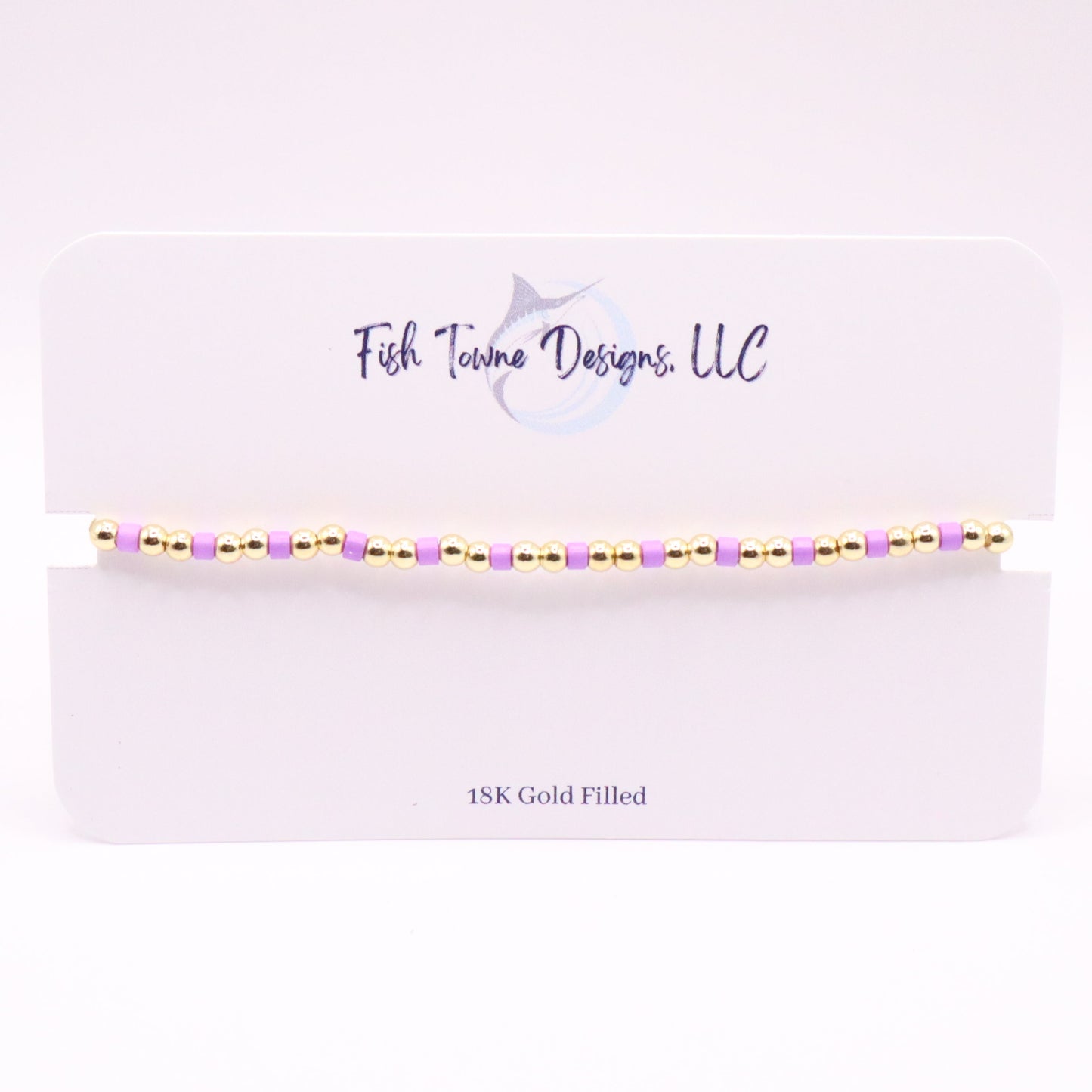 Gold and Orchid beaded bracelet on a white card with 'Fish Towne Designs, LLC' branding.