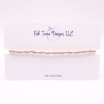 Gold and Orchid beaded bracelet on a white card with 'Fish Towne Designs, LLC' branding.