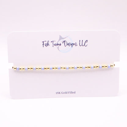Gold and lilac beaded bracelet on a white card with 'Fish Towne Designs, LLC' branding.
