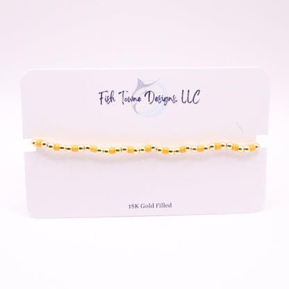 Gold and orange bracelet on a white card with 'Fish Towne Designs, LLC' branding.