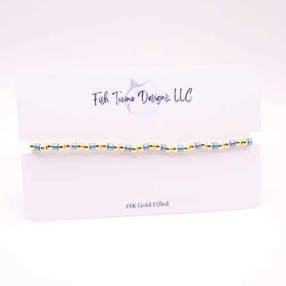 Gold and blue beaded bracelet on a white card with 'Fish Towne Designs, LLC' branding.