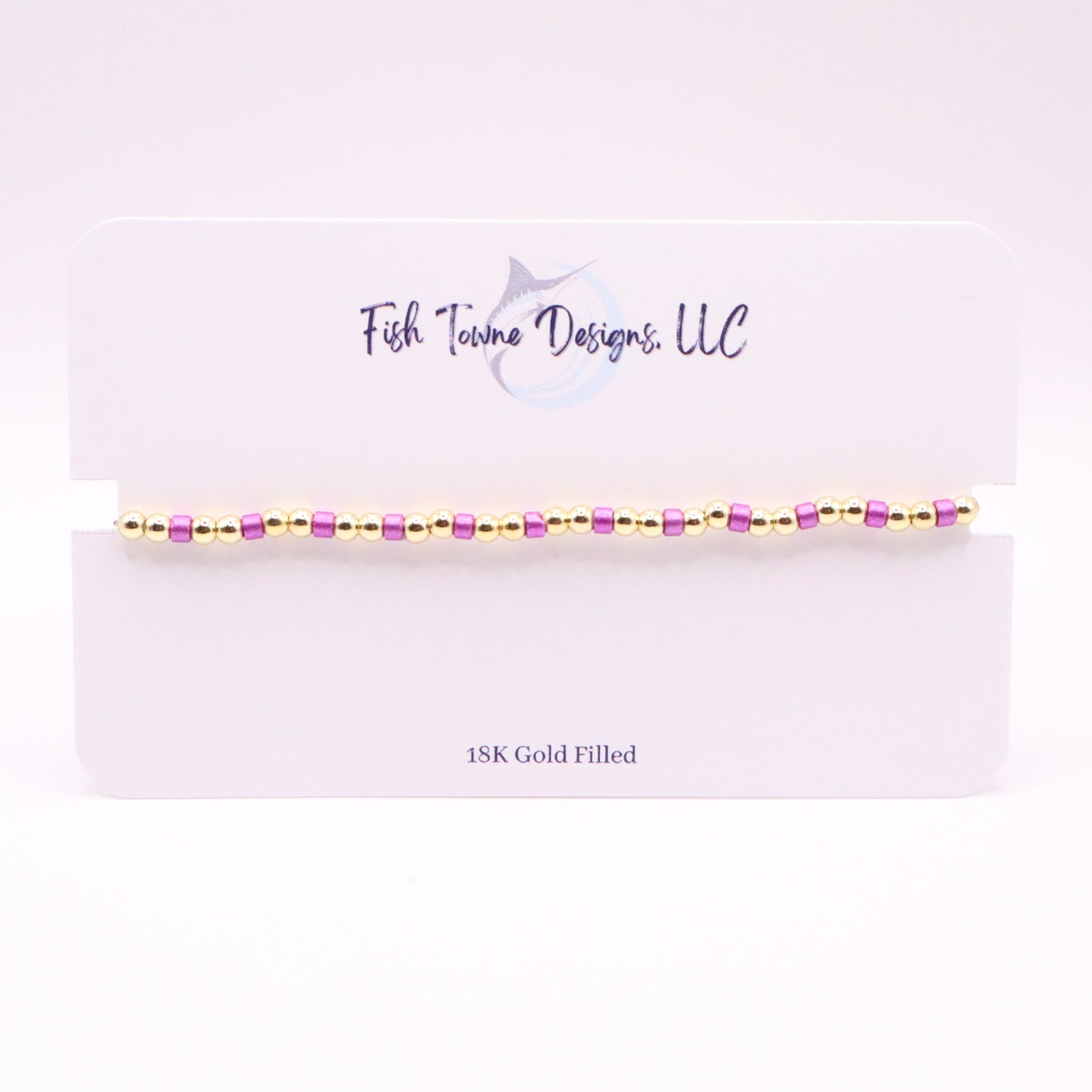  Gold and violet bracelet on a white card with 'Fish Towne Designs, LLC' branding.
