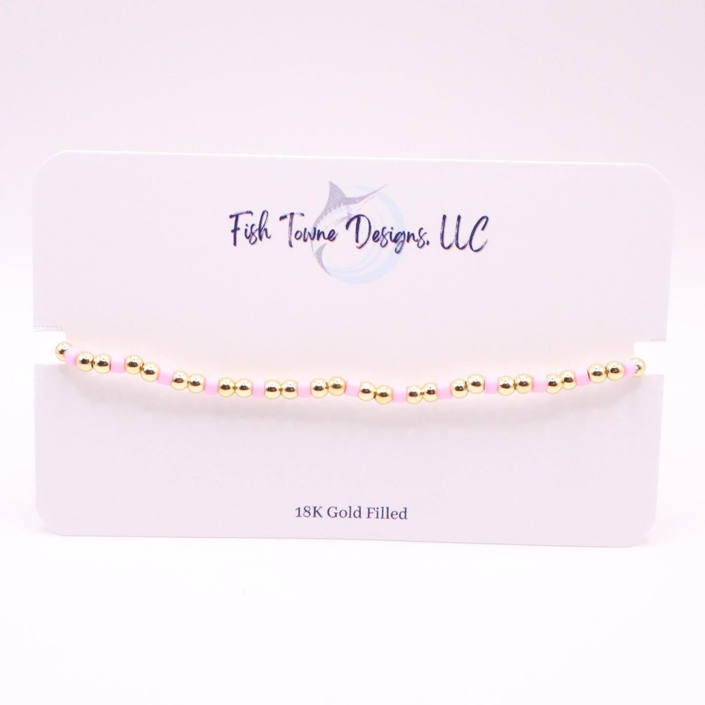 Gold and pink bracelet  on a white card with 'Fish Towne Designs, LLC' branding.