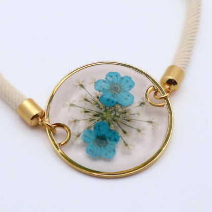 Delicate blue floral resin bracelet with gold charm and white cord lightweight handmade jewelry gift