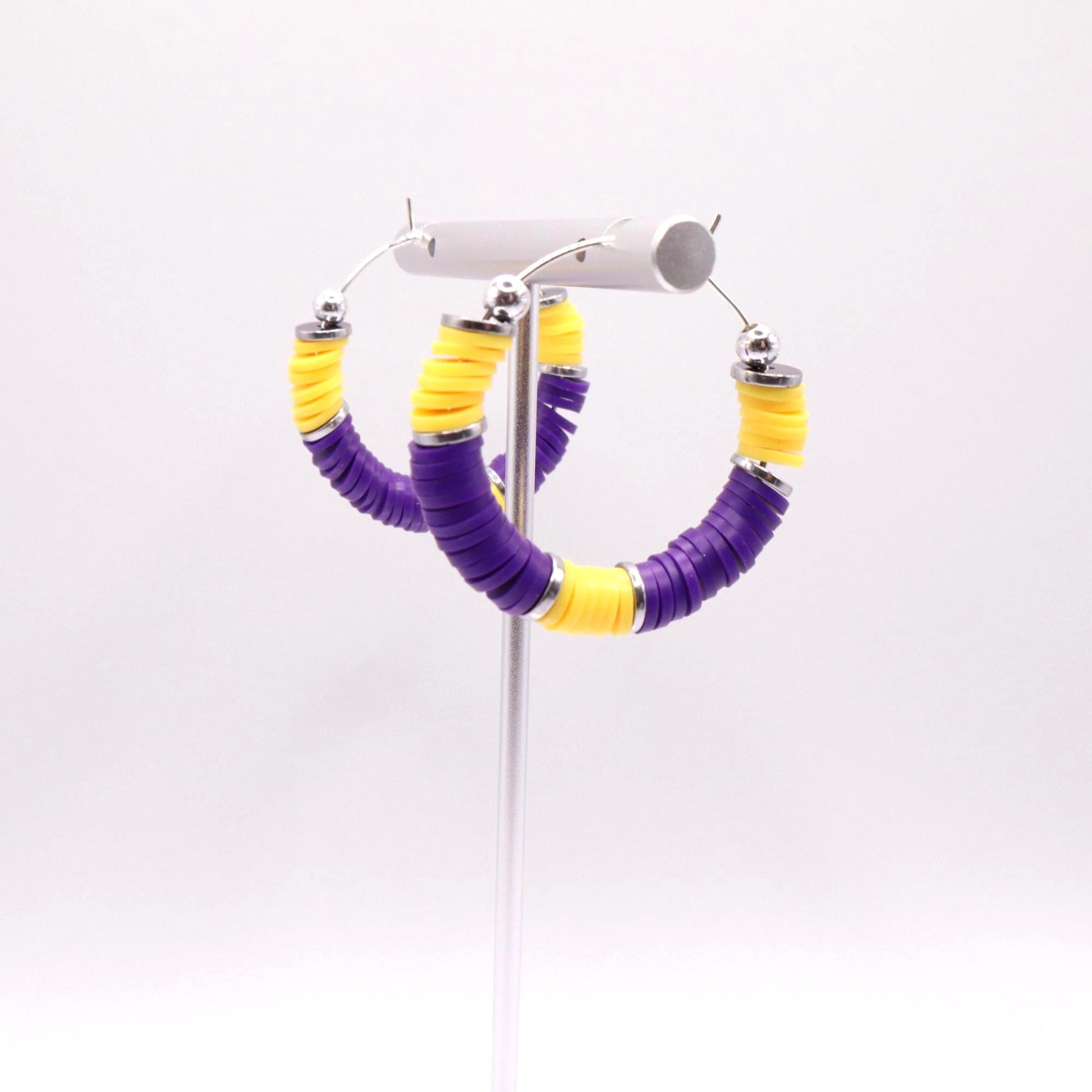 Purple and gold heishi bead hoop earrings with gold accents displayed on a branded card against a clean white background