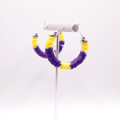 Purple and gold heishi bead hoop earrings with gold accents displayed on a branded card against a clean white background