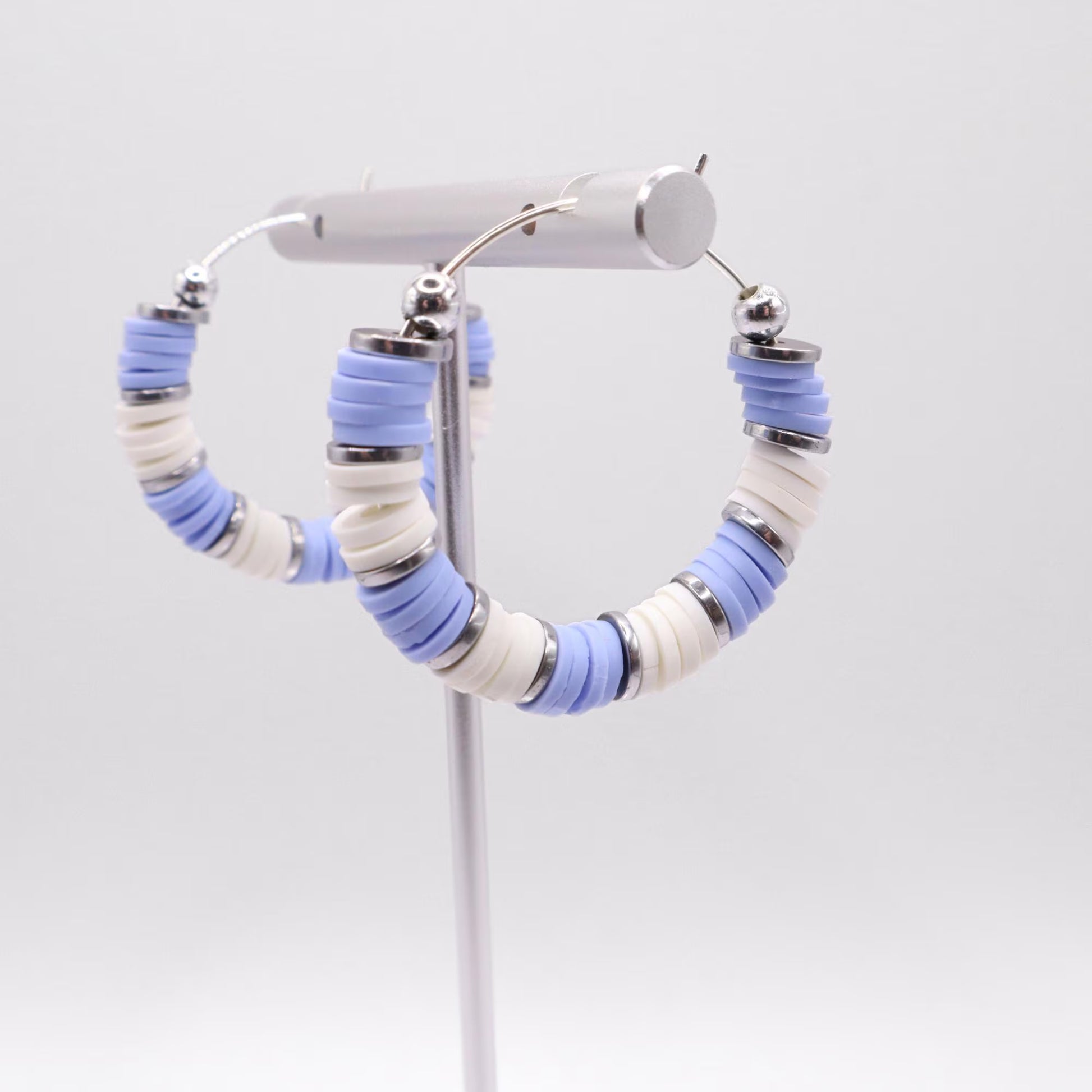 Light blue and white heishi bead hoop earrings with silver accents displayed on a branded card against a clean white background