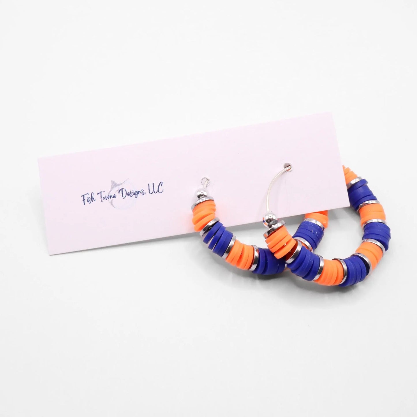 Handmade blue and orange polymer clay heishi bead hoop earrings with silver spacers shown on a white background with display card