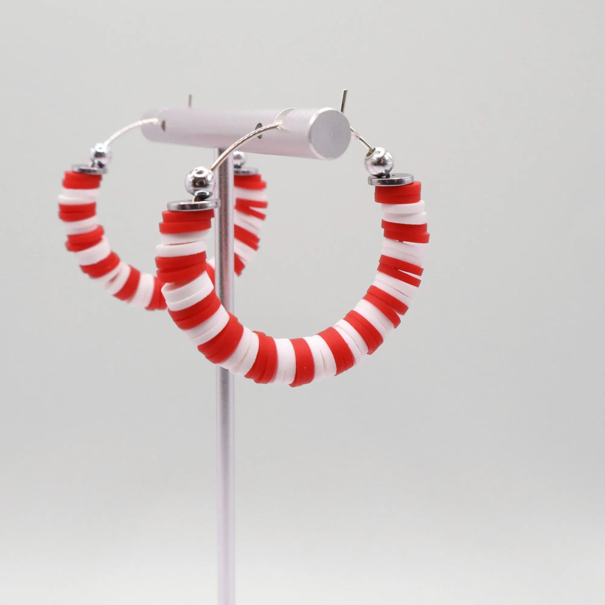 Red and white heishi bead hoop earrings with silver accents displayed on a branded card against a clean white background