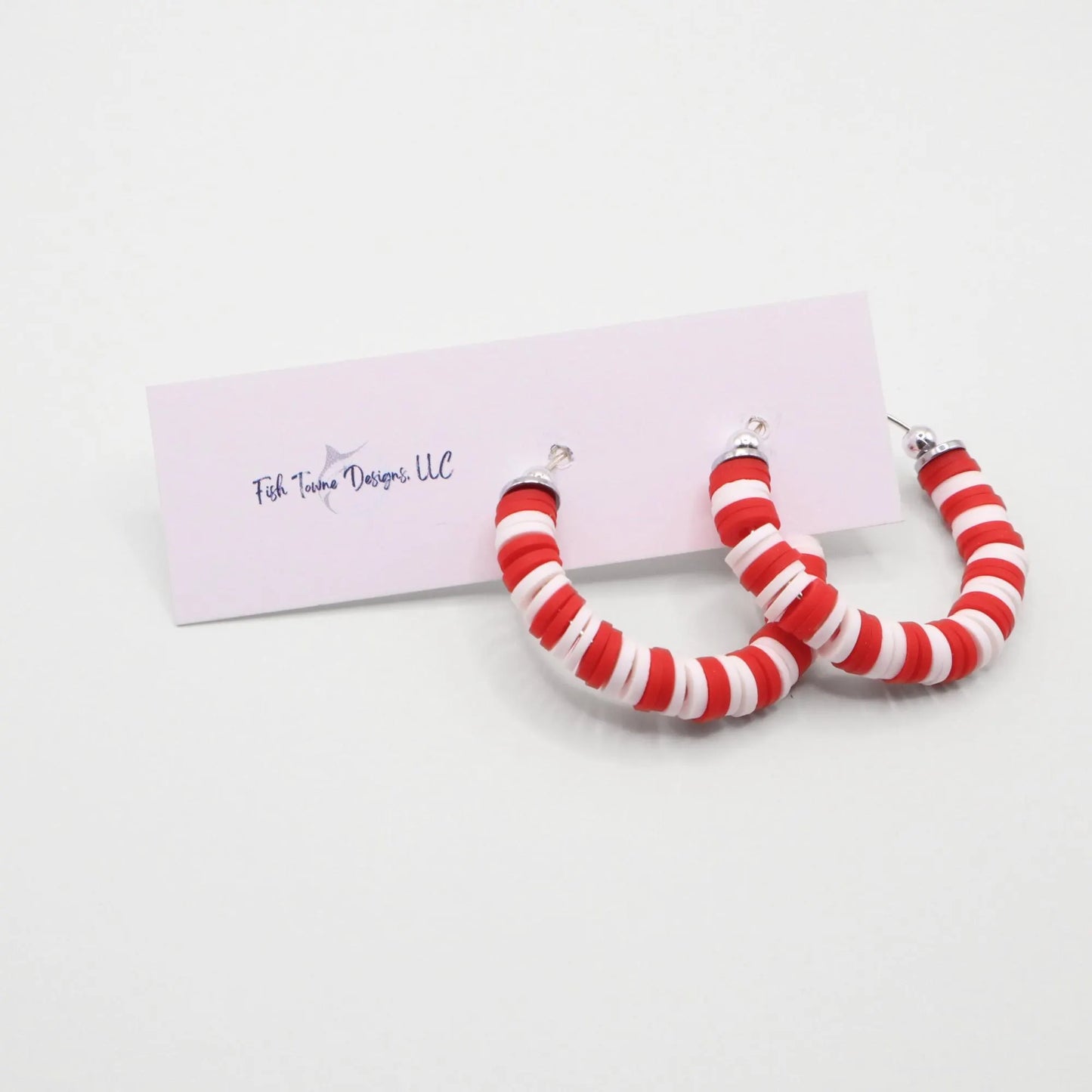 Red and white heishi bead hoop earrings with silver accents displayed on a branded card against a white background