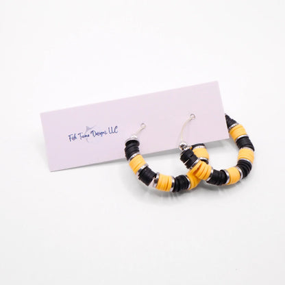 Handmade black and yellow polymer clay heishi bead hoop earrings with silver spacers shown on a white background with display card