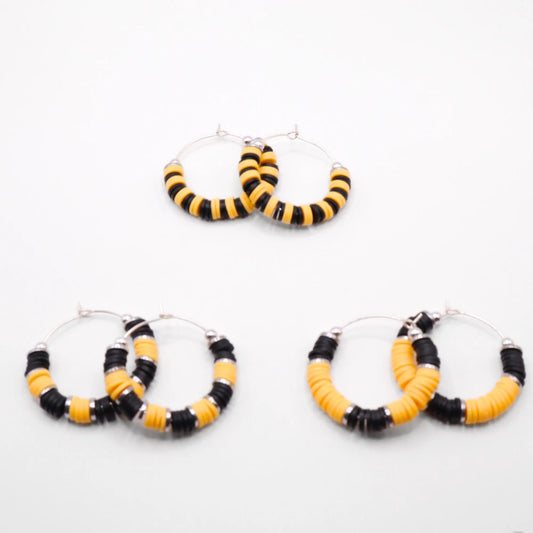 Set of three black and yellow heishi bead hoop earring styles arranged on a white background, showcasing size and pattern variations