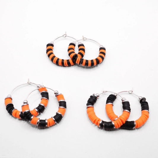 Set of three orange and black heishi bead hoop earring styles arranged on a white background, showcasing size and pattern variations