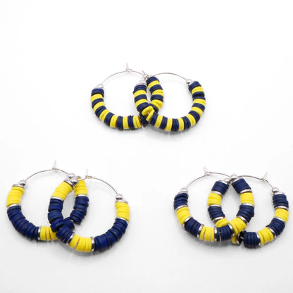 Set of three navy blue and yellow heishi bead hoop earring styles arranged on a white background, showcasing size and pattern variations