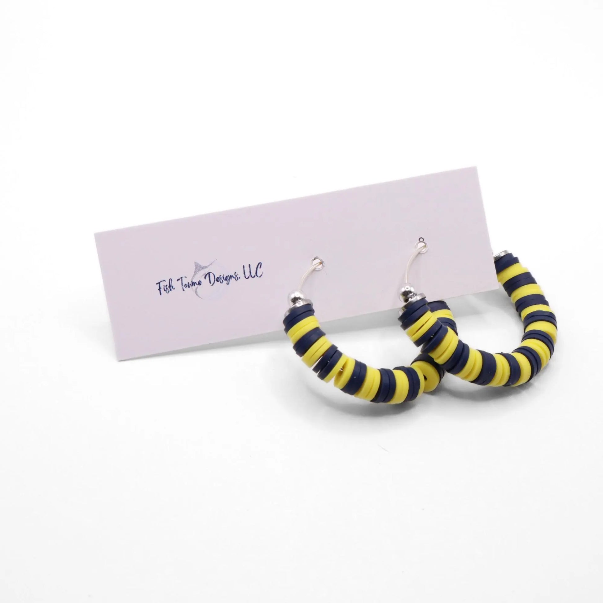Navy blue and yellow heishi bead hoop earrings with silver accents displayed on a branded card against a white background