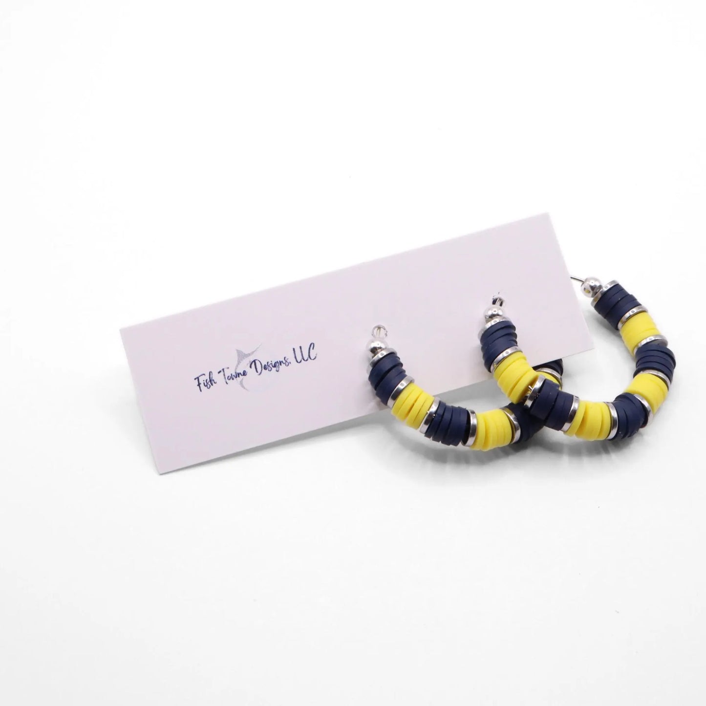 Handmade navy blue and yellow polymer clay heishi bead hoop earrings with silver spacers shown on a white background with display card