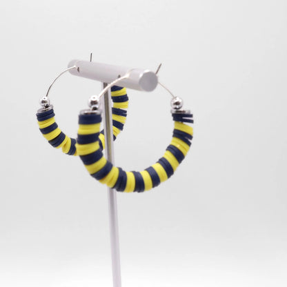 Navy blue and yellow heishi bead hoop earrings with silver accents displayed on a branded card against a clean white background