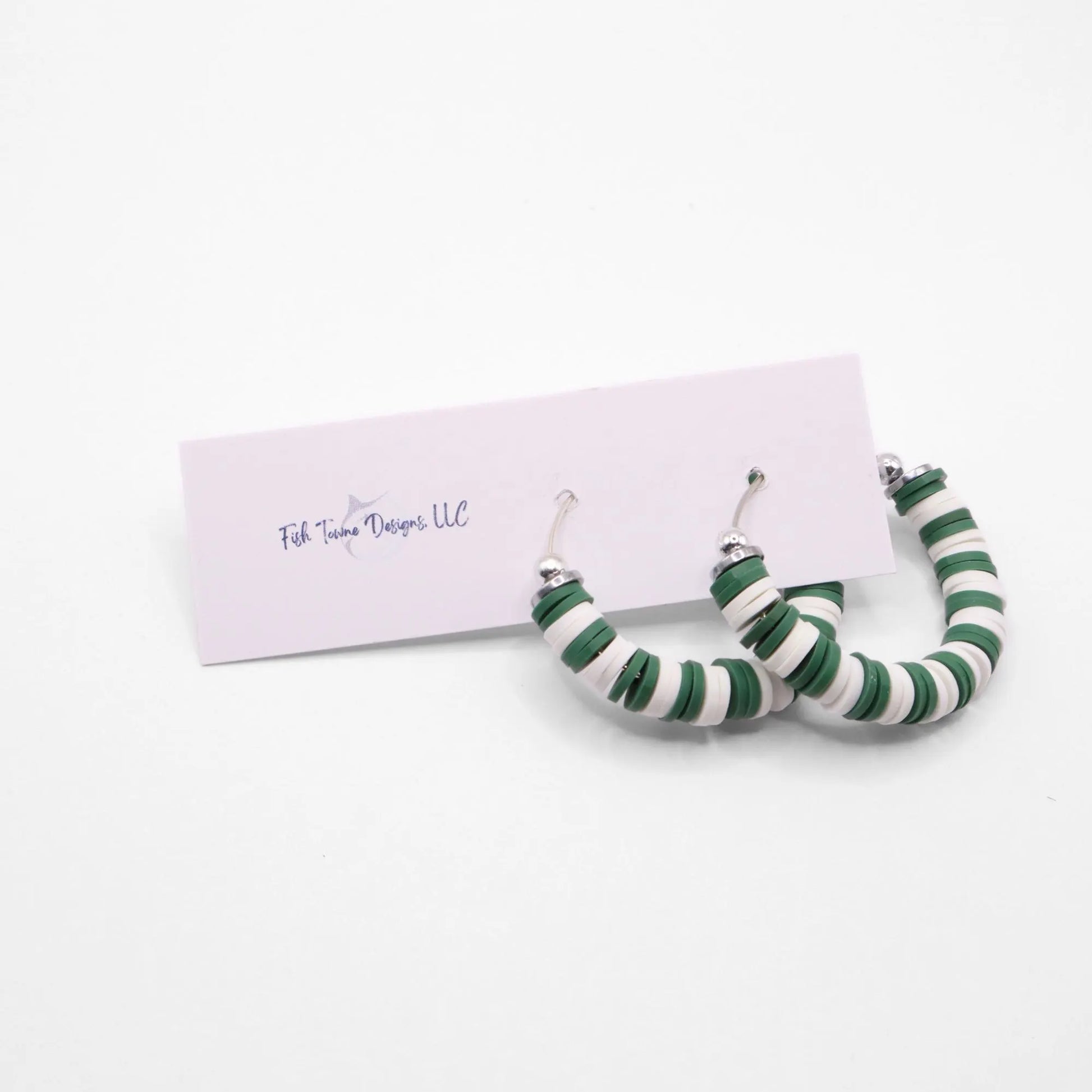 Green and white heishi bead hoop earrings with silver accents displayed on a branded card against a white background