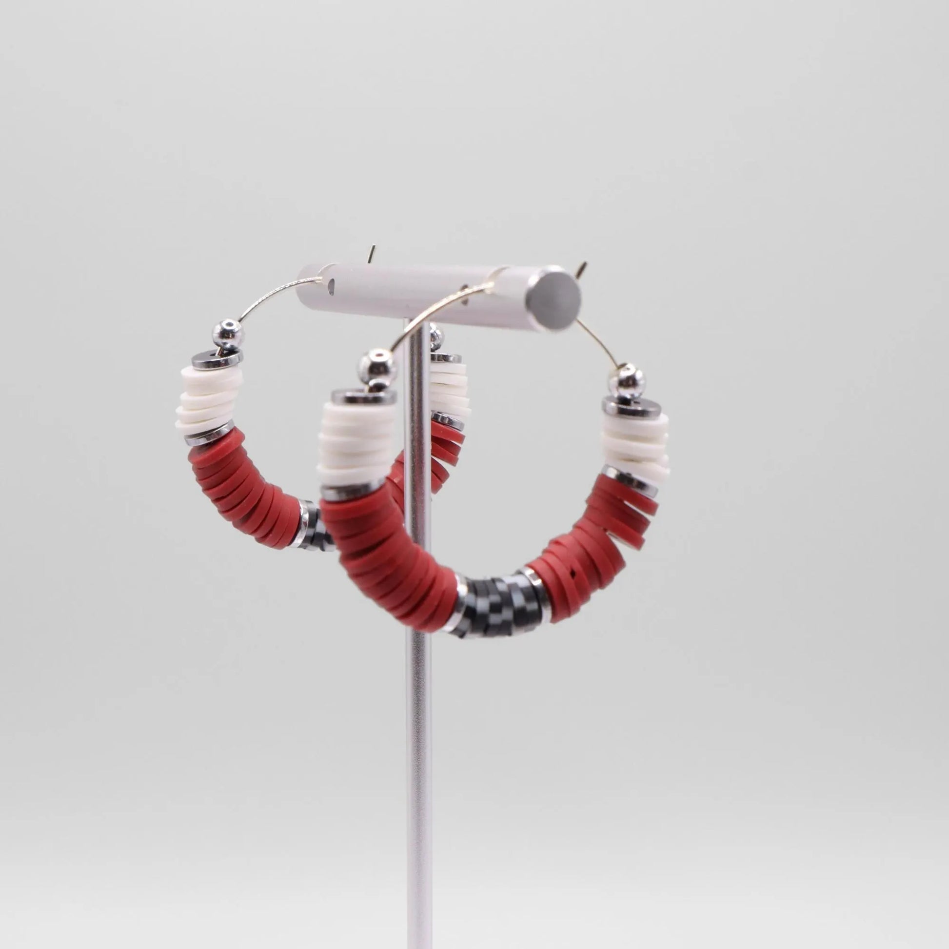 Crimson and houndstooth heishi bead hoop earrings with silver accents displayed on a branded card against a clean white background