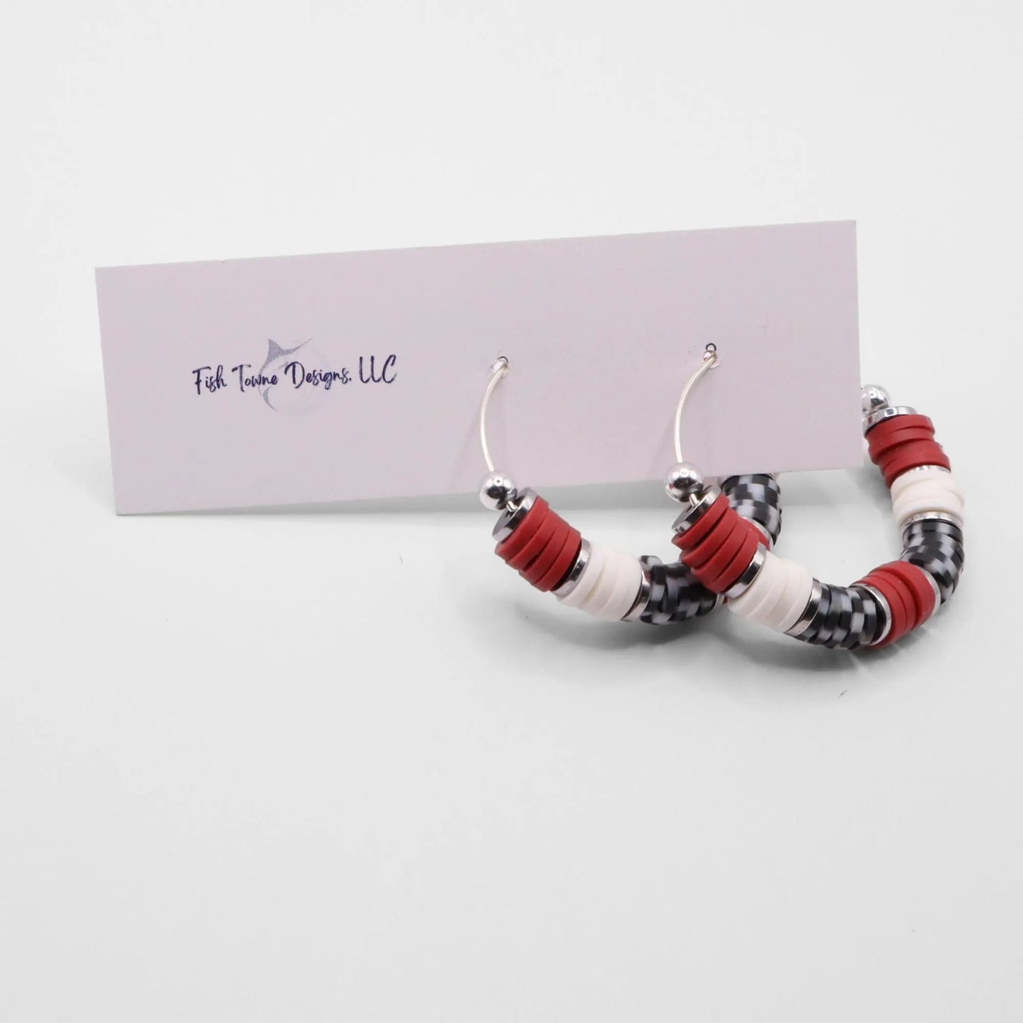 Handmade crimson and houndstooth polymer clay heishi bead hoop earrings with silver spacers shown on a white background with display card