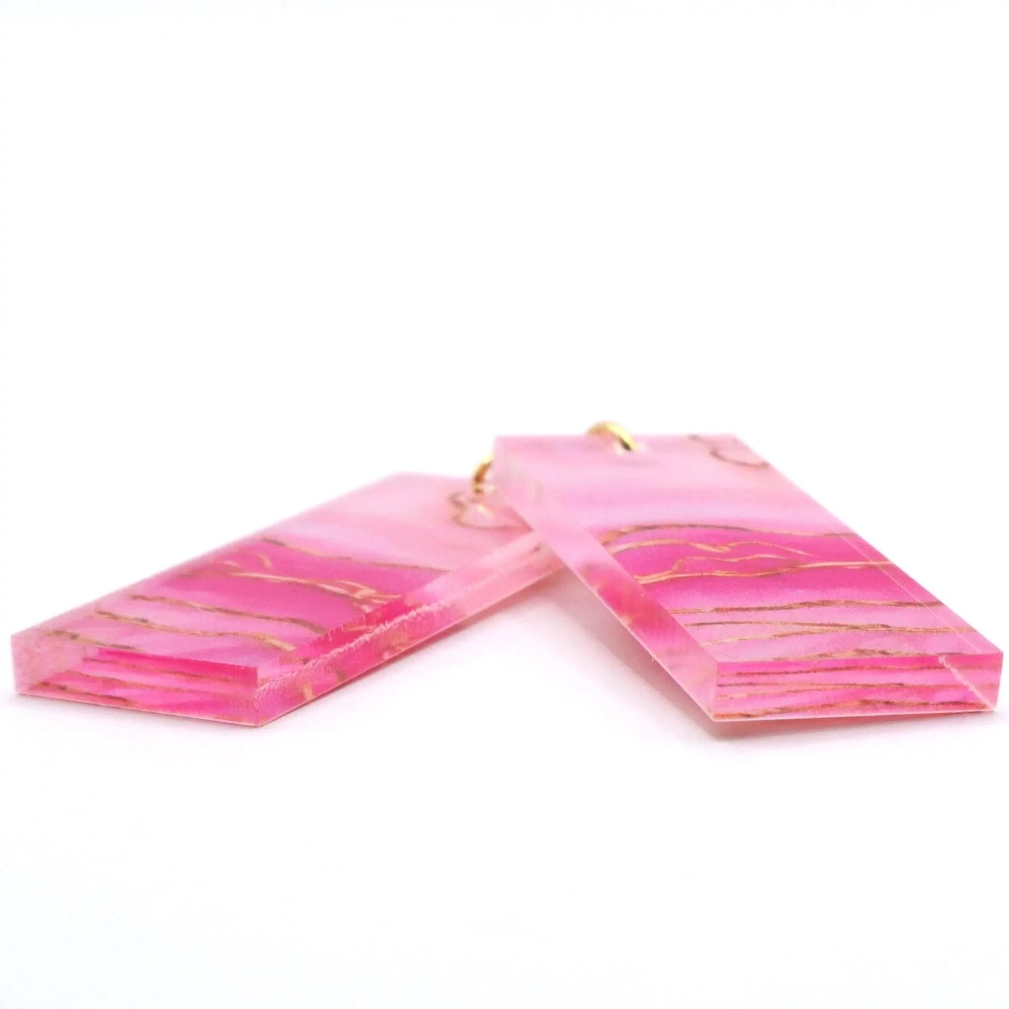 Pink marbled earrings with gold accents on a white background