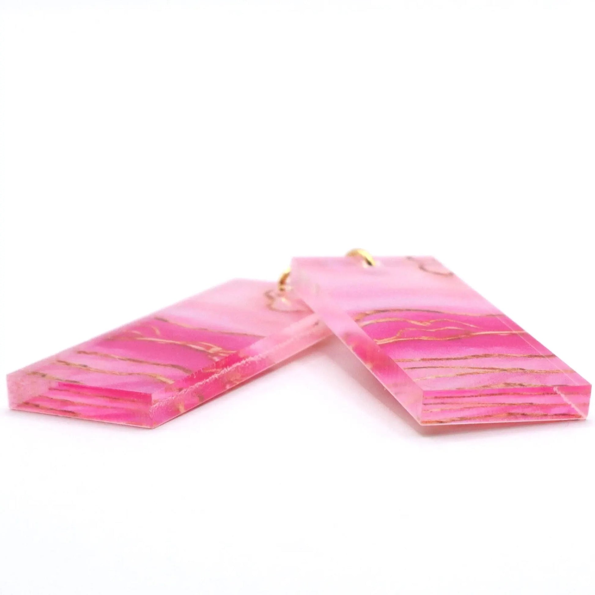 Pink marbled earrings with gold accents on a white background