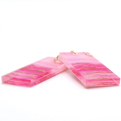 Pink marbled earrings with gold accents on a white background
