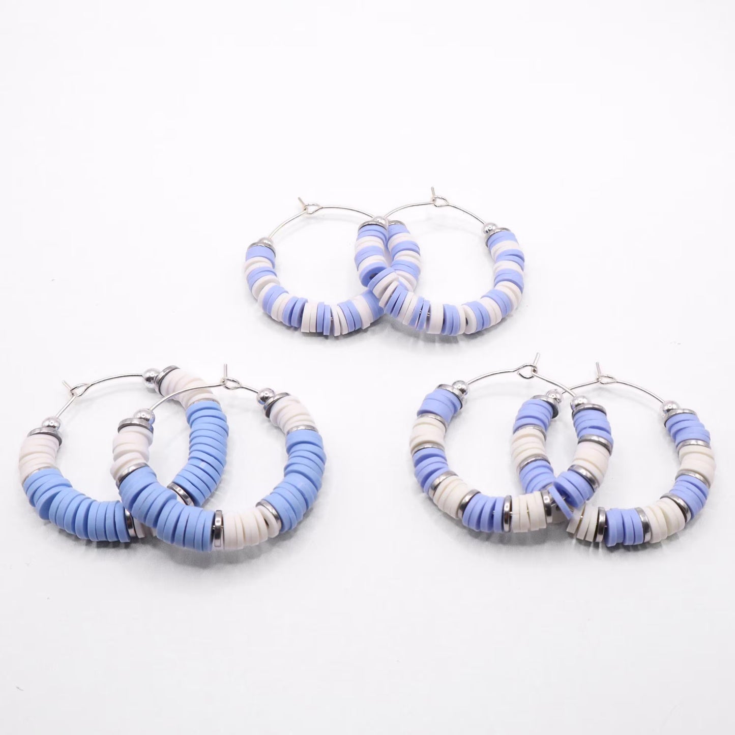 Set of three light blue and white heishi bead hoop earring styles arranged on a white background, showcasing size and pattern variations
