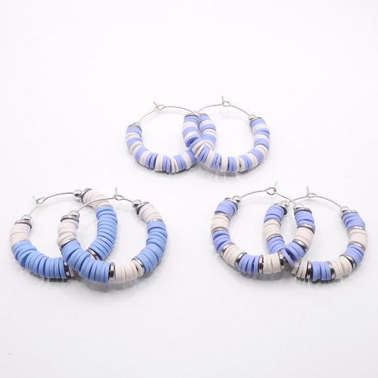 Set of three light blue and white heishi bead hoop earring styles arranged on a white background, showcasing size and pattern variations
