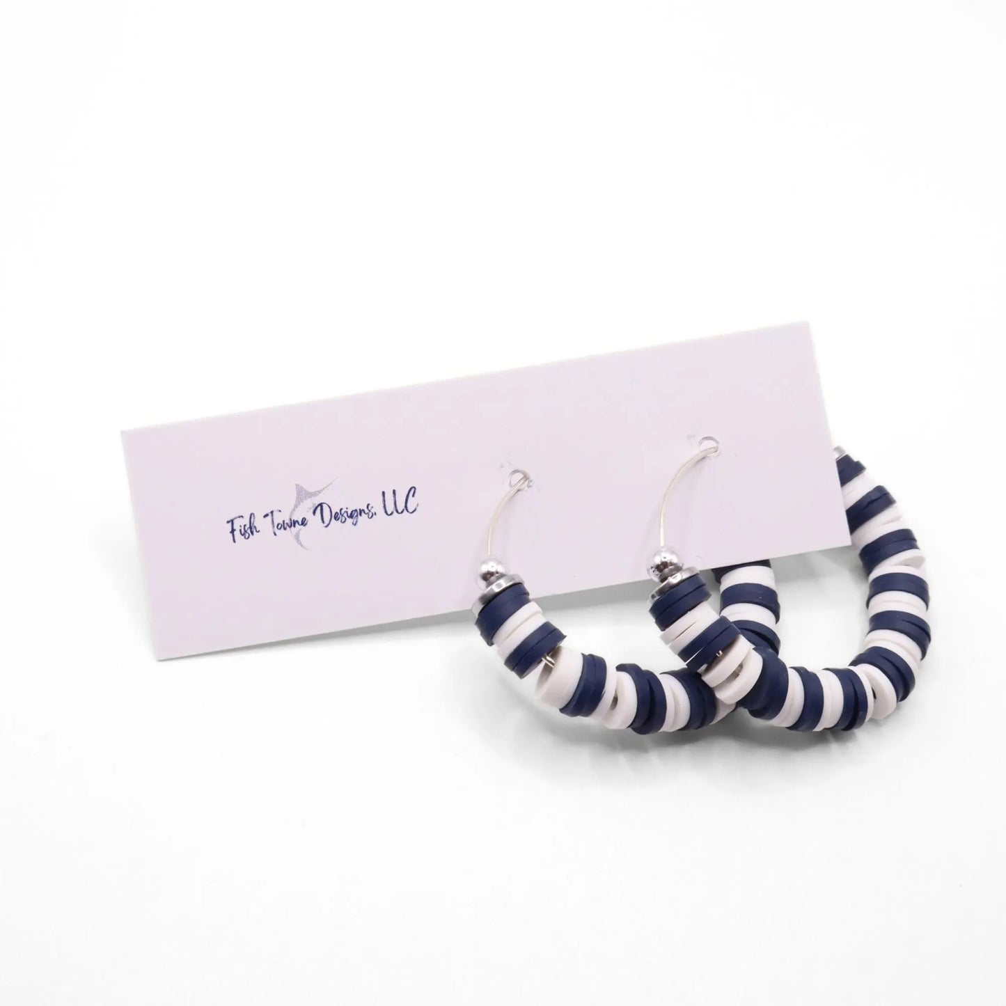 Navy blue and white heishi bead hoop earrings with silver accents displayed on a branded card against a white background