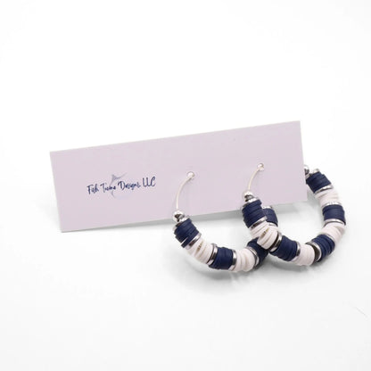 Handmade navy blue and white polymer clay heishi bead hoop earrings with silver spacers shown on a white background with display card