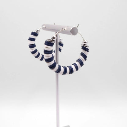 Navy blue and white heishi bead hoop earrings with silver accents displayed on a branded card against a clean white background