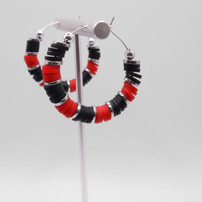 Red and black heishi bead hoop earrings with silver accents displayed on a branded card against a white background