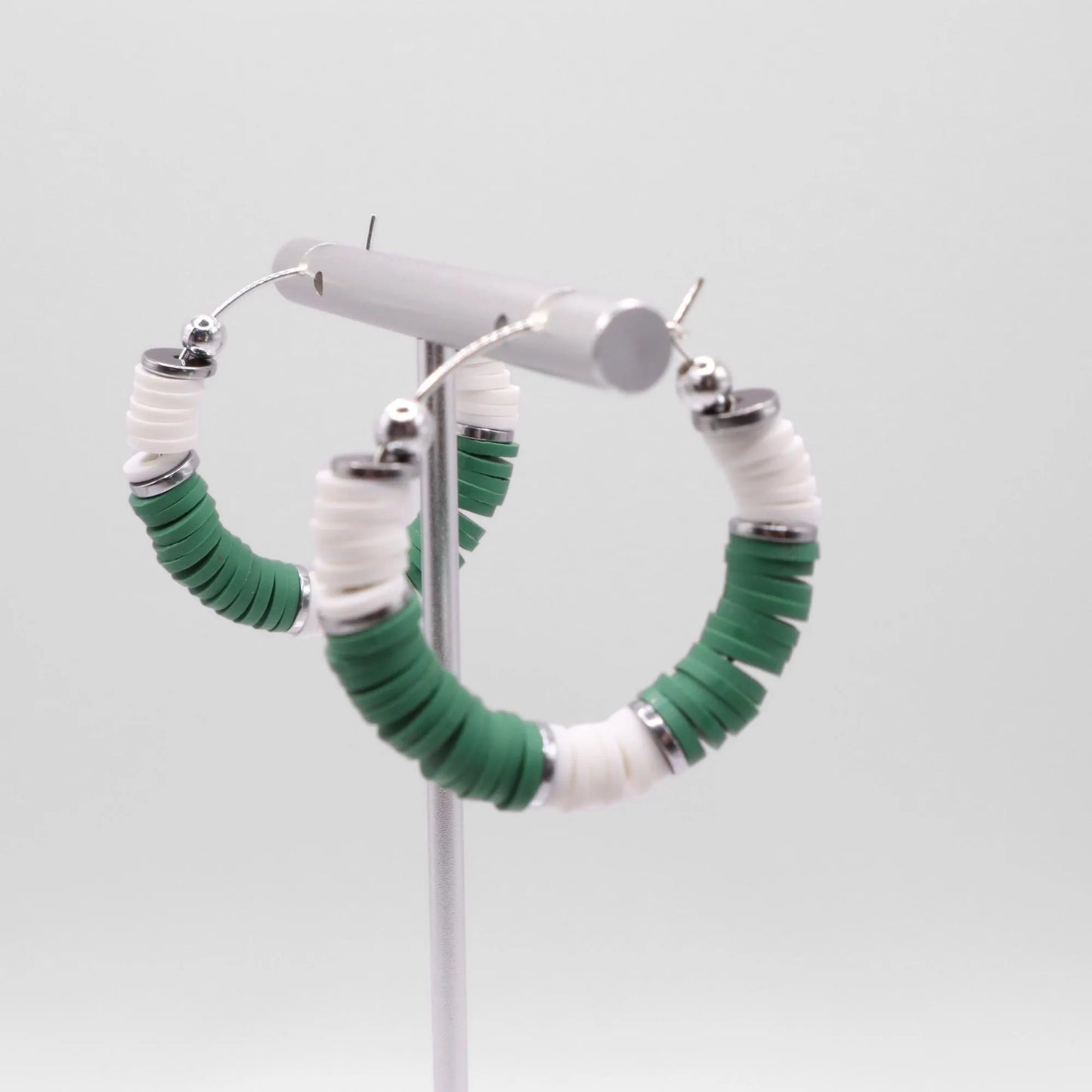 Green and white heishi bead hoop earrings with silver accents displayed on a branded card against a clean white background