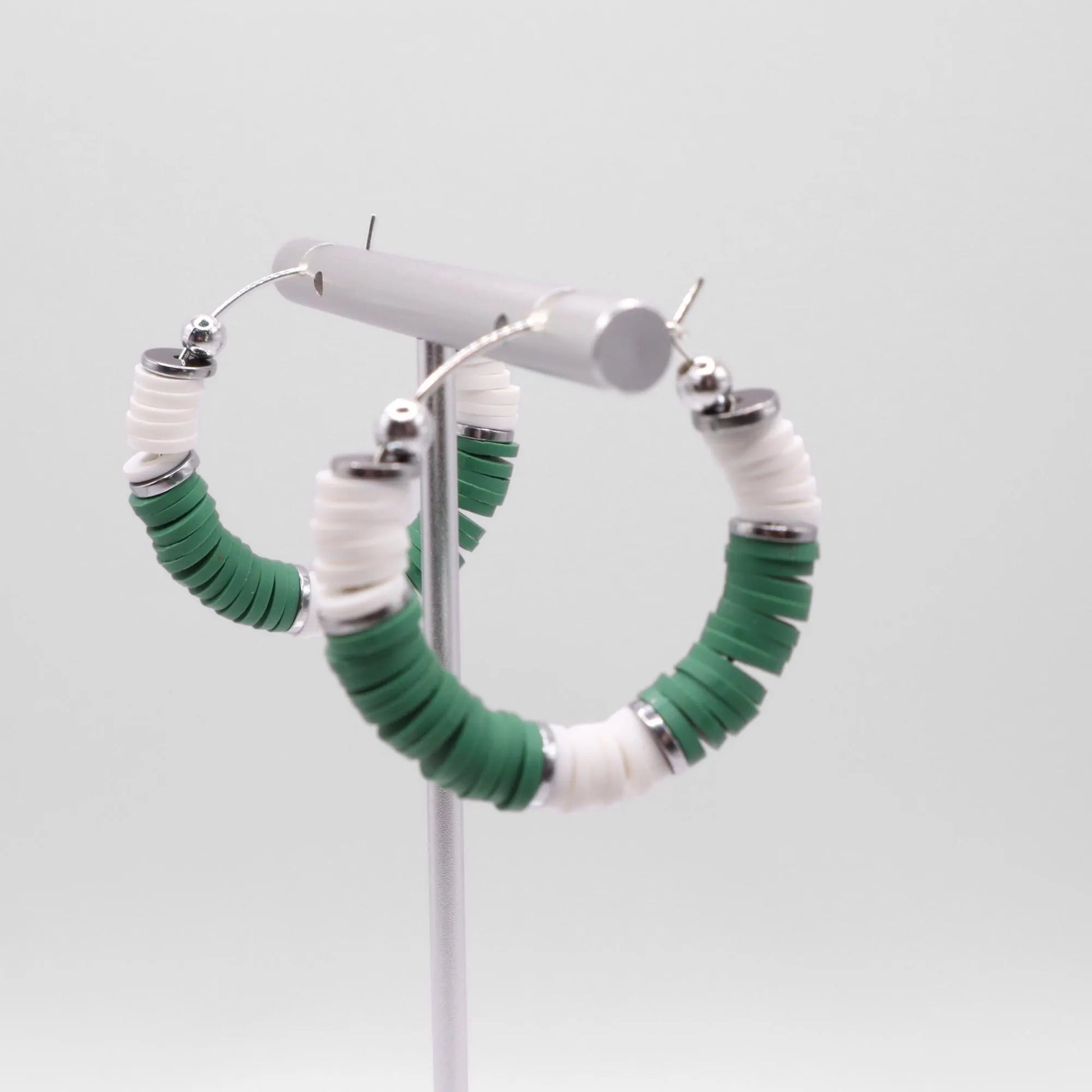 Green and white heishi bead hoop earrings with silver accents displayed on a branded card against a clean white background