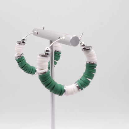 Green and white heishi bead hoop earrings with silver accents displayed on a branded card against a clean white background