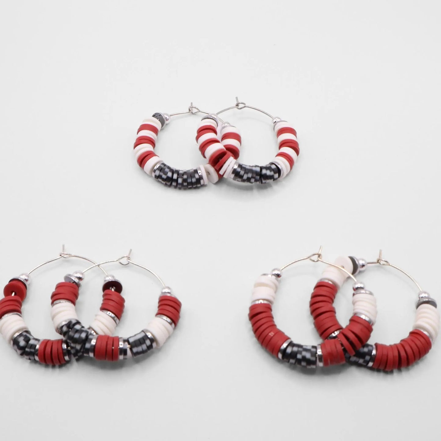 Set of three crimson and houndstooth heishi bead hoop earring styles arranged on a white background, showcasing size and pattern variations