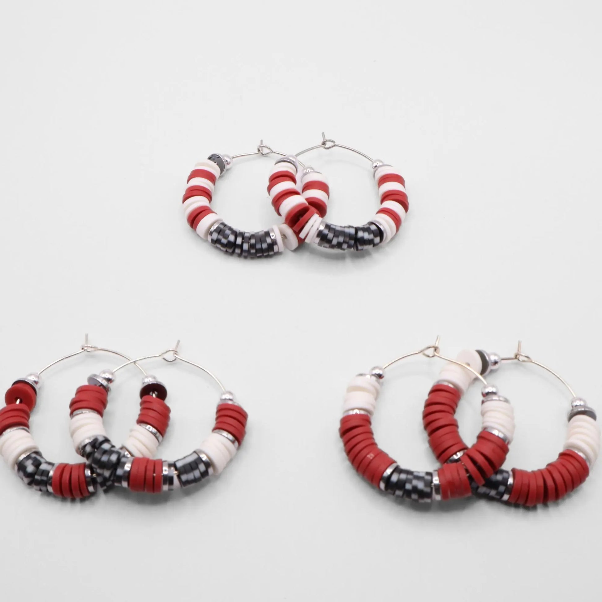 Set of three crimson and houndstooth heishi bead hoop earring styles arranged on a white background, showcasing size and pattern variations